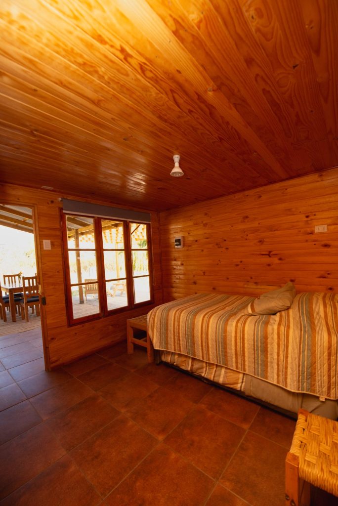 Dormitorio con cama matrimonial en la cabaña de madera