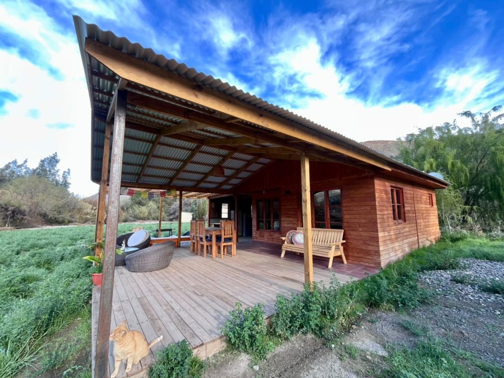 Cabaña de madera de Mystic Seron con su terraza techada bajo el cielo azul de Serón Norte