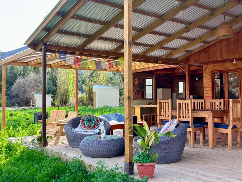 Terraza techada de la cabaña con sillones, banderines y plantas